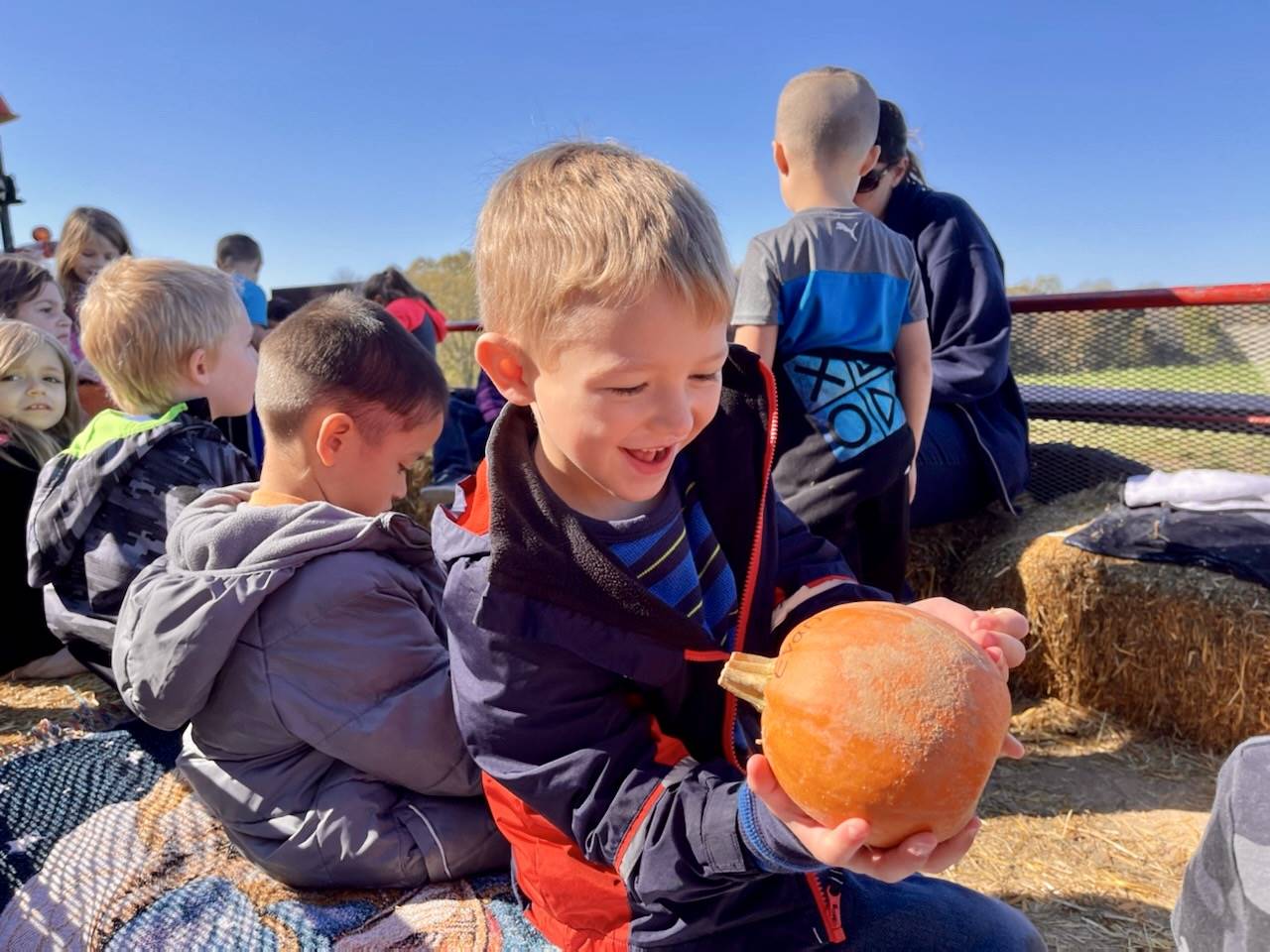 alt="student is happy with the pumpkin he picked at the pumpkin patch"